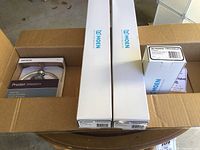 Box containing Moen bath fixtures including two Kingsley towel bars, Preston towel ring, and a Kingsley pivoting paper holder.