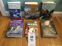 Six Napoleon-related books arranged on a wooden floor, view of all titles included, packed in a storage box.