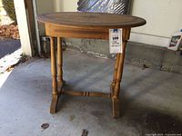 Side view of the vintage oval wooden table showing turned legs and stretcher base with single drawer.
