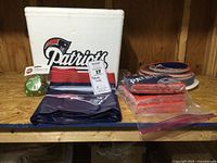 Photo showing Patriots cooler, Patriots napkins, red and navy tablecloth, two sizes of paper plates, clear plastic plates.