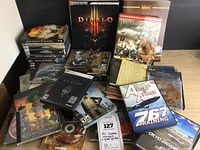 Large collection of PC game boxes, discs, manuals, including Diablo III and Praetorians among others, displayed on a tabletop.