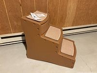 Side view of molded plastic pet steps featuring three carpeted steps in beige, with brown plastic structure and rivet accents.