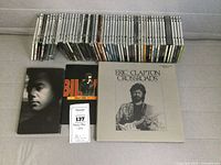 Wide shot of entire CD collection including Eric Clapton Crossroads box set, Billy Joel live CD, and other CDs lined up in rows.