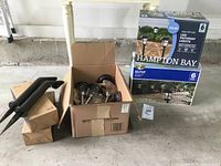 Photo of two boxes of Hampton Bay LED solar lights and a box with assorted clear-globe pathway lights and two out-of-box Mr Beam MB59 lights leant against them.