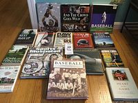Photo showing all 15 sports books arranged on a hardwood floor including classic titles and sports illustrated anniversary issue.