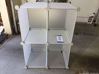 Front view showing the six cubby compartments arranged in two rows of three. White plastic panels with metal connectors visible at corners.