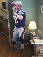 Full length photo of the 64-inch tall cardboard cutout of Tom Brady in a New England Patriots uniform, showing the figure in a throwing pose.