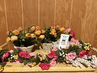 Two matching potted tulip arrangements, rose garland, and white flower bunches on wooden surface