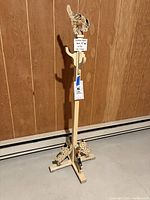 Full view of the tall wooden coatrack against a brown wall showing the cat figure on top, central hooks, and dog figures at the base.