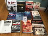 Overview of 12 WWII books arranged on a wooden floor showing titles and covers including 'The D-Day Companion,' 'World War II,' 'Operation Chastise,' and others.