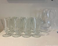 Front angle showing all 12 drinking glasses along with large glass pitcher behind them