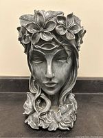 Full view of the goddess head planter showing facial features, floral crown, hair, and leaves.