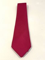 Full view of the Hermes solid pink silk tie laid flat to show color and shape.