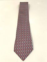 Full length view of Hermes tie decorated with a repeating fish pattern in red, white, and blue colors.