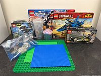 Photo of all LEGO boxes, loose bricks in containers, baseplates, and bags of LEGO pieces arranged on a black surface.