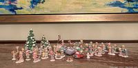 Wide view of all Precious Moments figurines including children, trees, vehicles, and accessories arranged on a shelf.