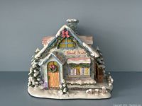 Front and angled view showing the wooden door with wreath, window with books, and detailed snow-covered decorations.