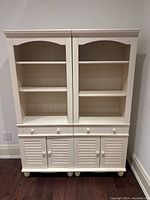 Front view of two identical white wooden bookshelves with open upper shelves, drawer, and double-door bottom storage.
