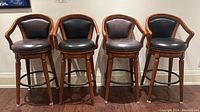 Four bar stools front view showing matching design, color variation, nailhead trim