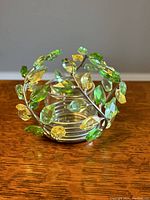 Tea light holder from front showing circular branch design with green and yellow crystal leaves.