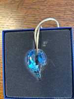 Photo of the blue Swarovski crystal ornament resting in original box with black foam padding.