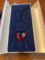 Red Swarovski crystal heart displayed in original box with blue velvet lining.