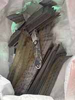 Bag containing multiple strips of gauge brad nails with a folding utility knife placed on top.