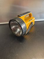 Yellow Craftsman brand flashlight with a large lens and side crank handle shown from a three-quarter front angle.