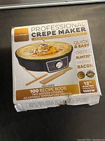 Box showing the product name, features, and included accessories such as two wooden utensils and a recipe book.