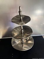 Full view of three-tier silver serving tray stand showing size and shape of each tier and finial handle on top