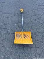 Full view of yellow snow shovel showing wide scoop and metal shaft