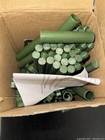 Top view of green plastic-coated metal plant stakes and clips inside a cardboard box with instructions.