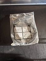 Photo of washing machine fill hose supply in original plastic package on black surface showing front side with printed installation instructions.