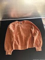 Full view of the apricot glaze quilted sweatshirt laid flat, showing front design and texture.