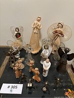 Collection of 14 angel figurines including various sizes and wing styles on a black surface.