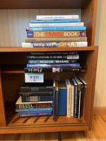 Stack of assorted travel and coffee table books with various titles visible on shelves