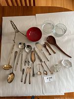 All items laid out on white paper showing assorted spoons, small bowls, and decorative glass items.