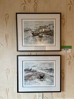 Two Lui Ming prints framed and hung on a kitchen wall, showing coastal and boat scenes.