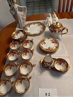 Full view of Golden Rose tea set with eight cups, eight saucers, teapot, creamer, sugar bowl, serving plates and two figurines
