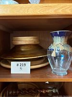Wooden serving dishes stacked and decorative glass vase with blue top and tassels on the shelf