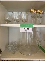 Wine decanter with stopper on bottom shelf, with brandy snifters and various stemmed glasses above