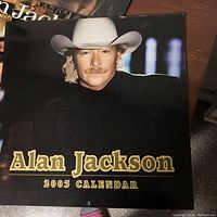 Front cover of 2003 Alan Jackson calendar showing Alan Jackson wearing a white cowboy hat and black outfit.