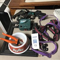 Photo of the electronic fence system, leash, harness, nail clippers, and dog bowl arranged on a table surface.