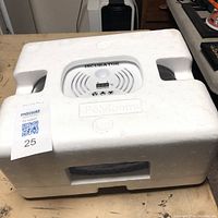 Closed incubator in white polyfoam packaging, showing control area with temperature display and vents.