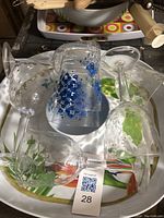 Plastic chip and dip bowl with tropical leaf and flower pattern, two clear plastic wine glasses and two plastic drinking glasses (one with blue floral design).