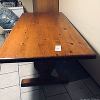 Top view of a large pine wood dining table with natural knots and grain, medium brown finish, showing normal wear and some marks on the tabletop.