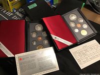 Two black vinyl folders each containing an uncirculated set of 1989 Canadian coins with red satin inner covers and accompanying informational inserts from the Royal Canadian Mint.