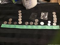 All coins laid out on black cloth with handwriting label showing coin years and types.
