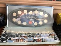 Three Canadian Millennium coin sets from 2000 including one with coins mounted on black display board with plastic cover over, shown with a winter-themed box beneath.