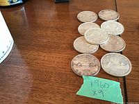 Group of nine 1960 Canadian silver dollars displayed on wooden surface, front and reverse visible